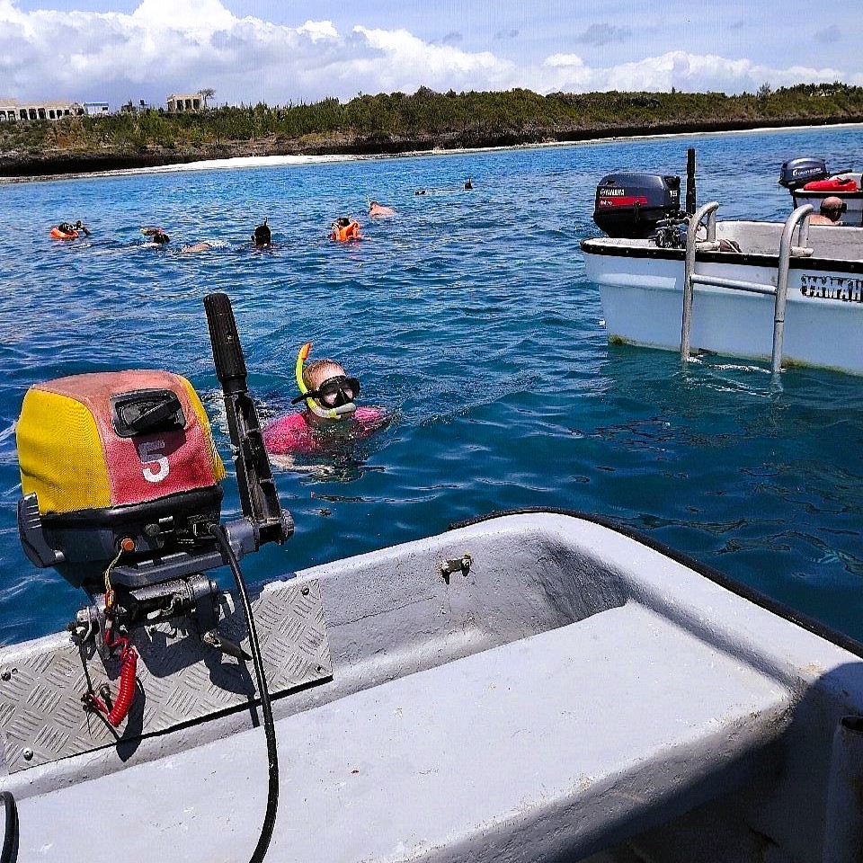 Guests snorkeling above coral reefs at Mnemba Island